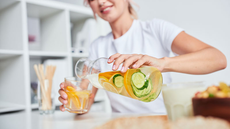 Mulher a servir água aromatizada com pepino e citrinos